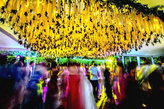 Gente bailando en una fiesta con un techo decorado con lirios